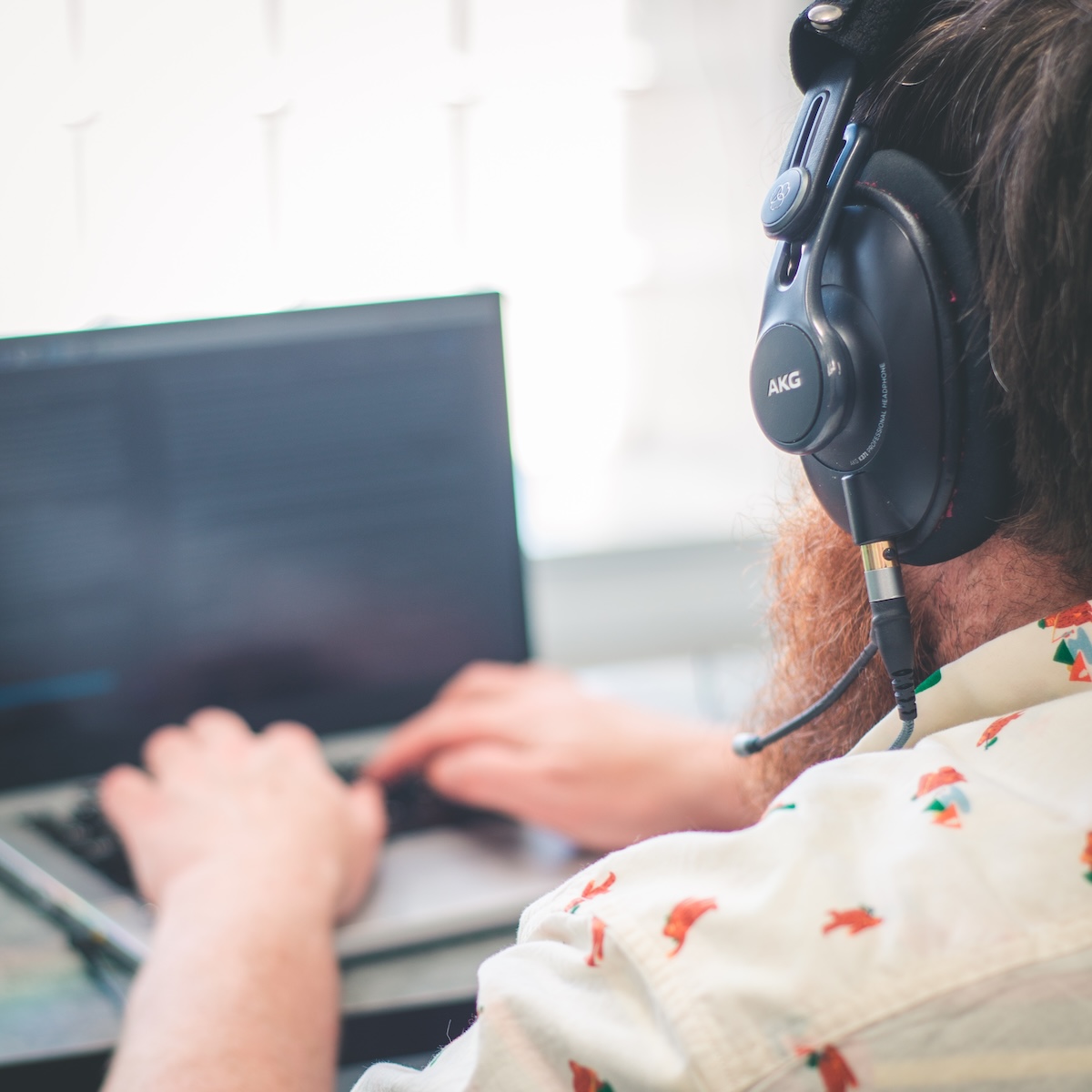 Adam typing on his laptop with headphones on